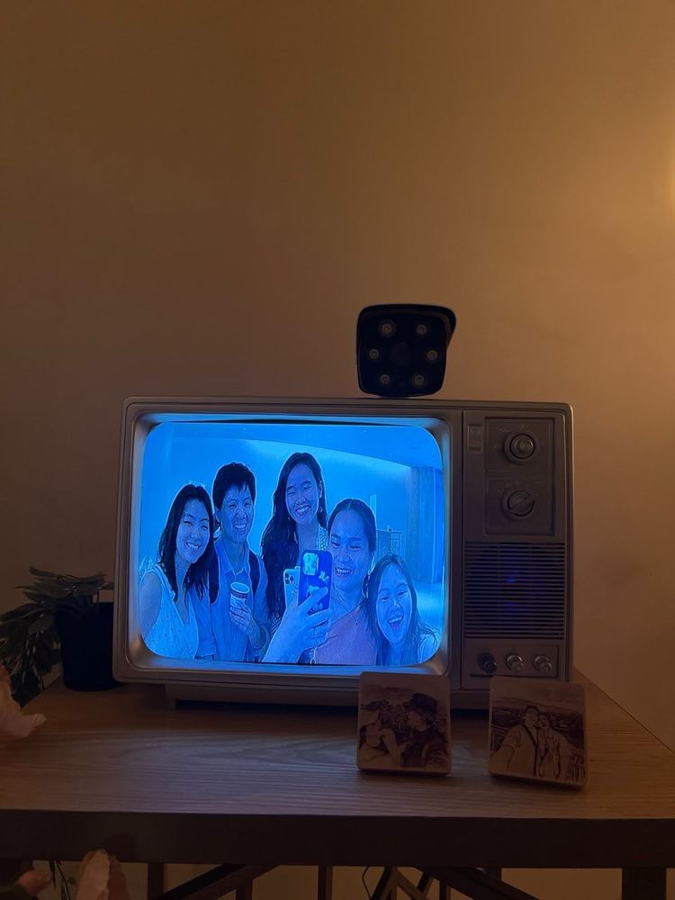 Guests smiling on the vintage TV screen with printed instant photos on the table at a wedding