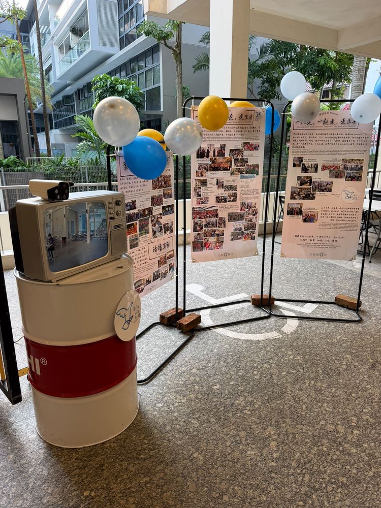 Vintage TV set up on a barrel alongside anniversary photo displays at a church event