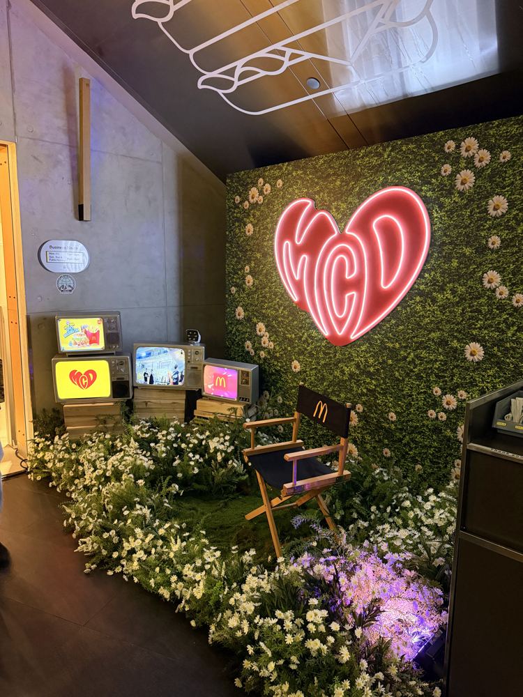 Vintage TVs among daisies and a neon heart sign at the McDonald's K-pop Rave Party